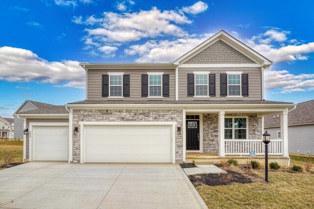596 Courtright Dr E, Pickerington, OH 43147 - view of front of house featuring a porch, concrete driveway, stone siding, and an attached garage