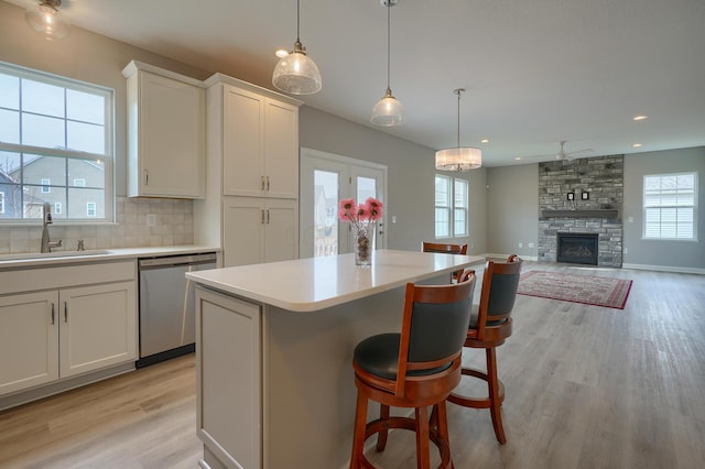 596 Courtright Dr E, Pickerington, OH 43147 - kitchen featuring stainless steel dishwasher, a sink, light wood-style floors, light countertops, and backsplash