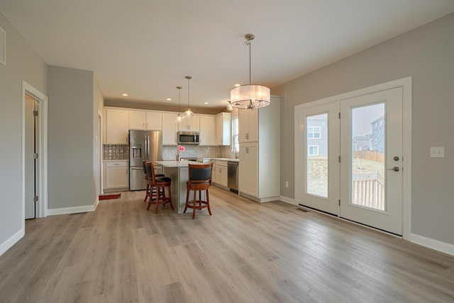 596 Courtright Dr E, Pickerington, OH 43147 - kitchen featuring appliances with stainless steel finishes, light wood finished floors, a breakfast bar area, tasteful backsplash, and a kitchen island