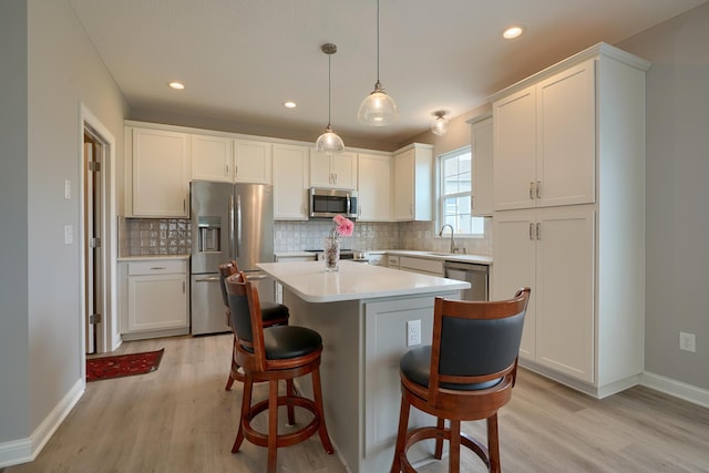 596 Courtright Dr E, Pickerington, OH 43147 - kitchen featuring appliances with stainless steel finishes, light wood finished floors, backsplash, a kitchen bar, and recessed lighting