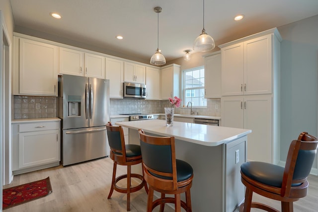 596 Courtright Dr E, Pickerington, OH 43147 - kitchen featuring appliances with stainless steel finishes, a sink, light countertops, light wood-style floors, and a kitchen breakfast bar