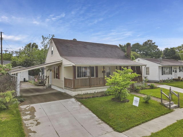 view of front of home with driveway, covered porch, a shingled roof, a front yard, and an attached carport