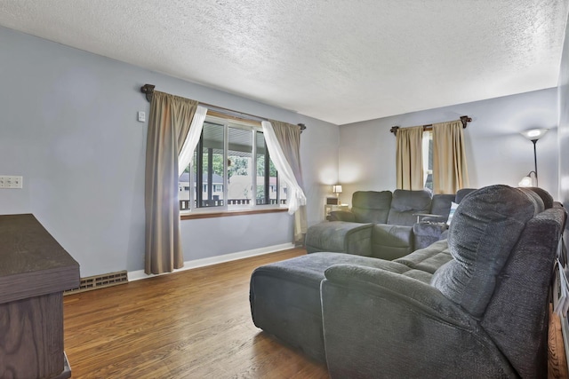 living room featuring plenty of natural light, a textured ceiling, wood finished floors, and baseboards