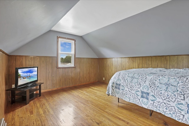 bedroom featuring wood finished floors, lofted ceiling, and wood walls