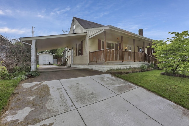 view of front of home featuring concrete driveway, a shed, an outdoor structure, a porch, and a front lawn