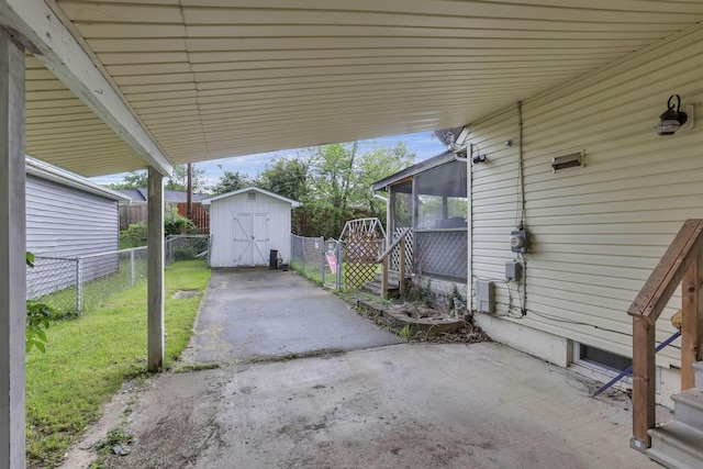 view of patio / terrace with a shed, a sunroom, an outbuilding, and a carport