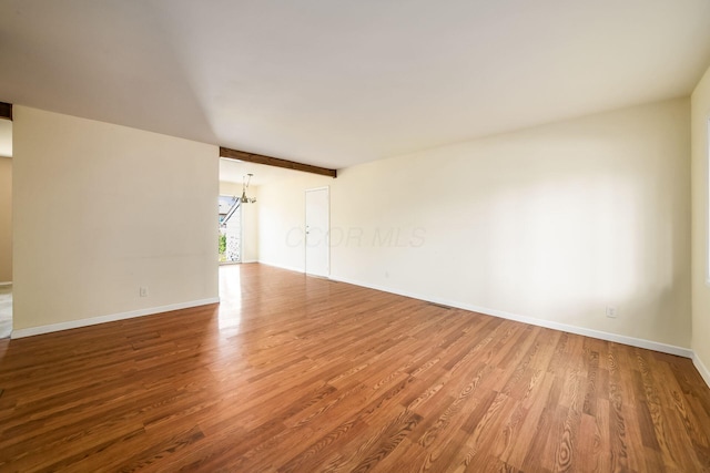 1512 Shanley Dr, Columbus, OH 43224 - unfurnished room with wood finished floors, baseboards, a chandelier, and beam ceiling
