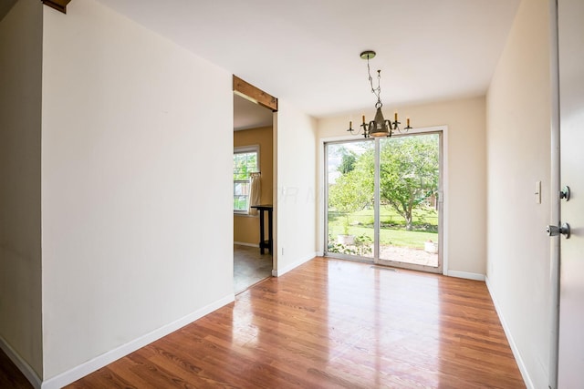 1512 Shanley Dr, Columbus, OH 43224 - unfurnished dining area featuring wood finished floors, a chandelier, and baseboards