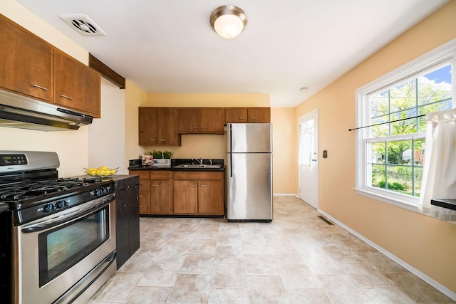 1512 Shanley Dr, Columbus, OH 43224 - kitchen featuring appliances with stainless steel finishes, under cabinet range hood, a sink, dark countertops, and brown cabinets