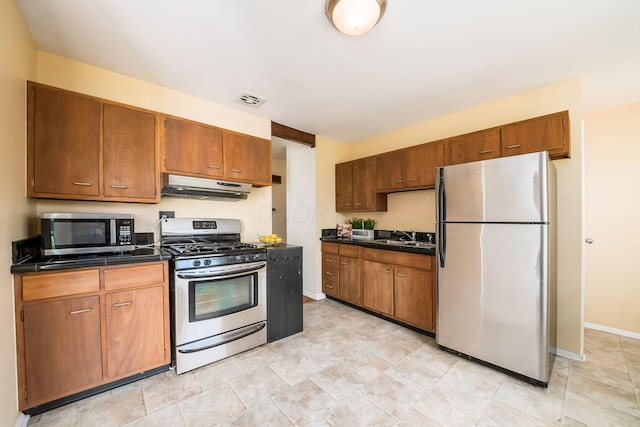 1512 Shanley Dr, Columbus, OH 43224 - kitchen featuring stainless steel appliances, under cabinet range hood, dark countertops, and brown cabinets