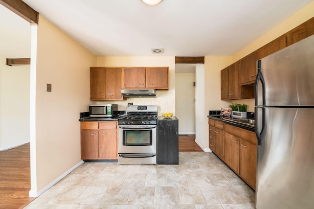 1512 Shanley Dr, Columbus, OH 43224 - kitchen featuring appliances with stainless steel finishes, under cabinet range hood, dark countertops, baseboards, and brown cabinets