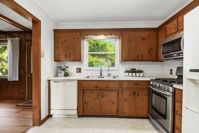 738 Stinson Dr, Columbus, OH 43214 - kitchen featuring stainless steel appliances, light countertops, wood walls, brown cabinets, and light wood-style floors