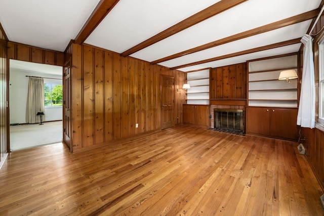 738 Stinson Dr, Columbus, OH 43214 - unfurnished living room with beamed ceiling, a fireplace with flush hearth, light wood finished floors, wood walls, and a baseboard radiator