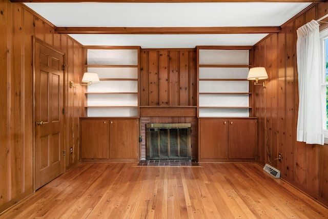 738 Stinson Dr, Columbus, OH 43214 - unfurnished living room featuring light wood-style flooring, a brick fireplace, wooden walls, and healthy amount of natural light