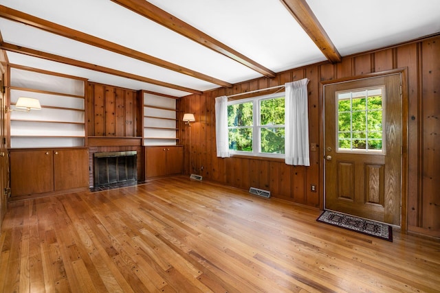 738 Stinson Dr, Columbus, OH 43214 - unfurnished living room with beamed ceiling, light wood-type flooring, a brick fireplace, and wooden walls