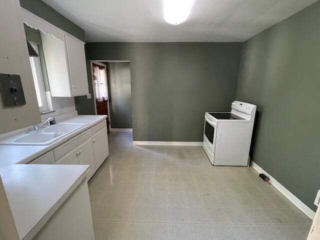 635 E Dominion Blvd, Columbus, OH 43214 - kitchen with electric stove, a sink, light countertops, white cabinets, and baseboards