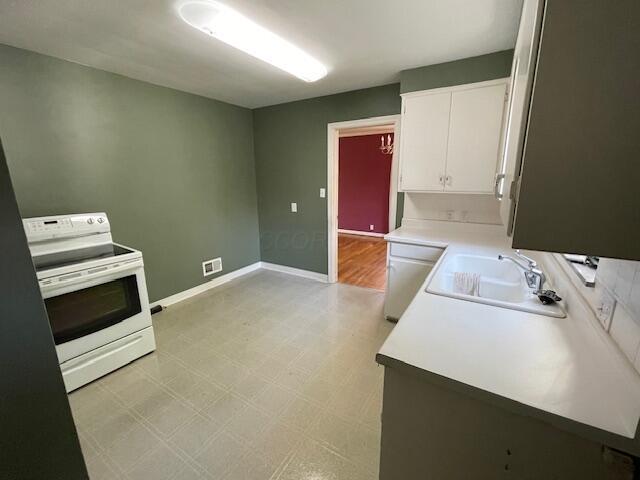 635 E Dominion Blvd, Columbus, OH 43214 - kitchen with white electric range oven, a sink, white cabinetry, light floors, and light countertops