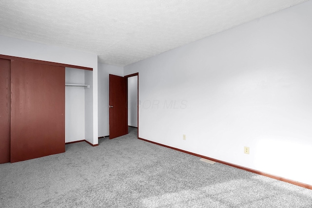 unfurnished bedroom featuring carpet floors, baseboards, a closet, and a textured ceiling