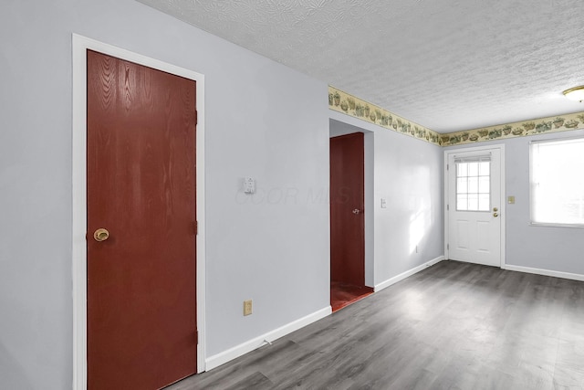 foyer with a textured ceiling, wood finished floors, and baseboards