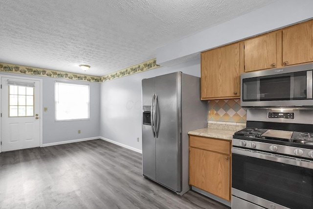 kitchen featuring appliances with stainless steel finishes, light countertops, wood finished floors, baseboards, and a textured ceiling