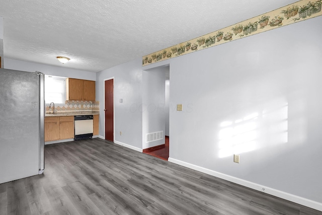 unfurnished living room with dark wood finished floors, a textured ceiling, baseboards, and a sink