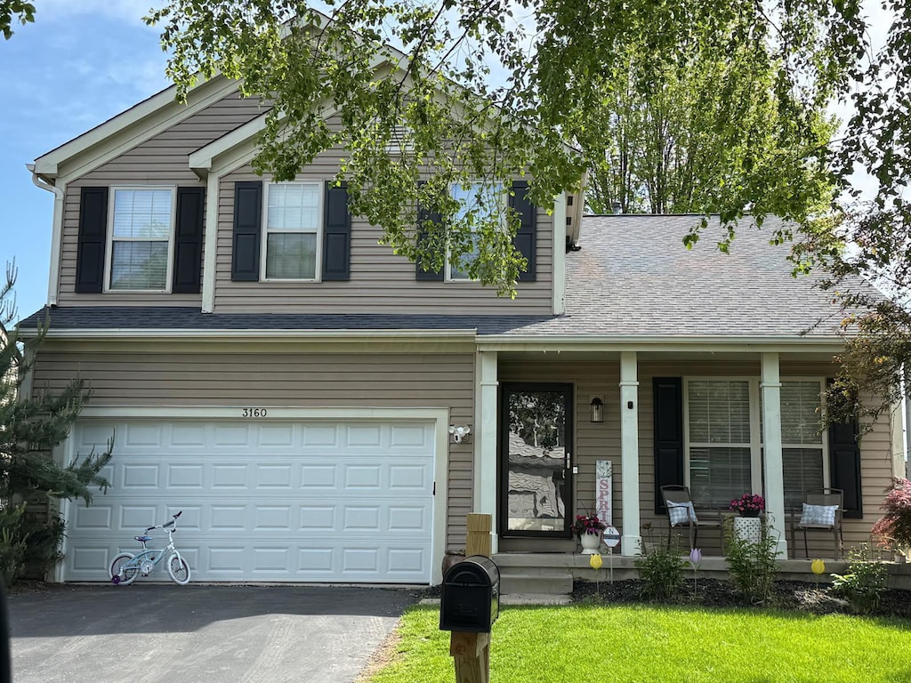 view of front facade with a porch, a garage, driveway, and a shingled roof