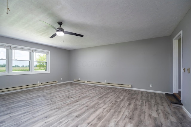 13216 Sheley Road Nw, Jeffersonville, OH 43128 - empty room with baseboard heating, wood finished floors, a ceiling fan, a textured ceiling, and baseboards
