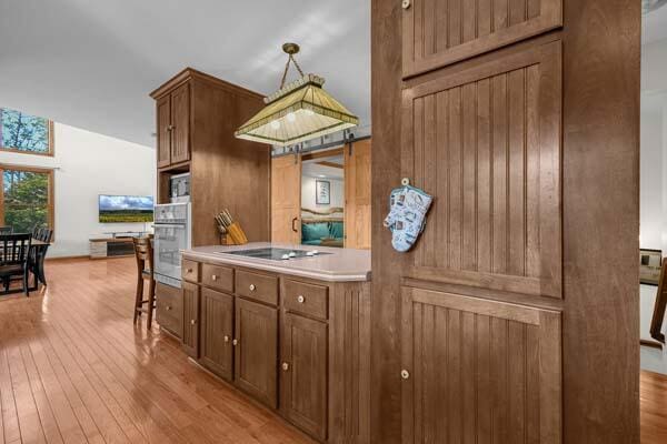 29002 Rockstull Rd, Sugar Grove, OH 43155 - kitchen with oven, black electric stovetop, light wood finished floors, and brown cabinetry