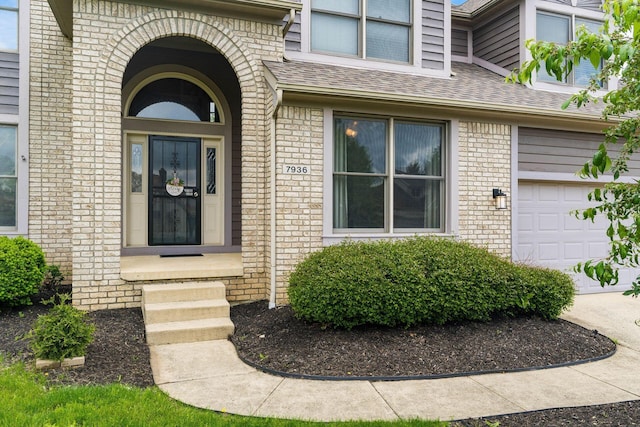 7936 Slate Ridge Blvd, Reynoldsburg, OH 43068 - view of exterior entry featuring brick siding, a shingled roof, and a garage