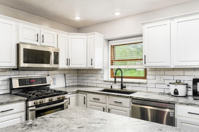 7936 Slate Ridge Blvd, Reynoldsburg, OH 43068 - kitchen with stainless steel appliances, a sink, white cabinetry, light stone counters, and recessed lighting