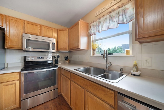 kitchen featuring appliances with stainless steel finishes, a sink, tasteful backsplash, and light countertops