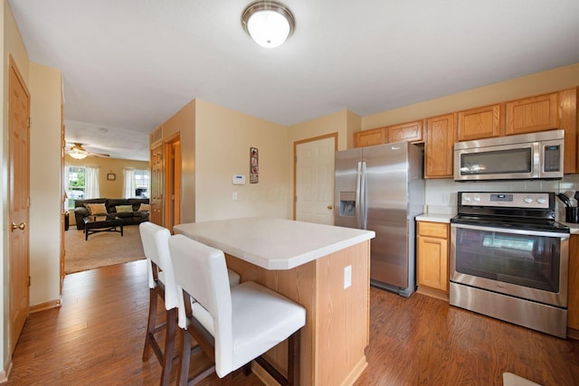 kitchen featuring appliances with stainless steel finishes, wood finished floors, a breakfast bar area, and light countertops