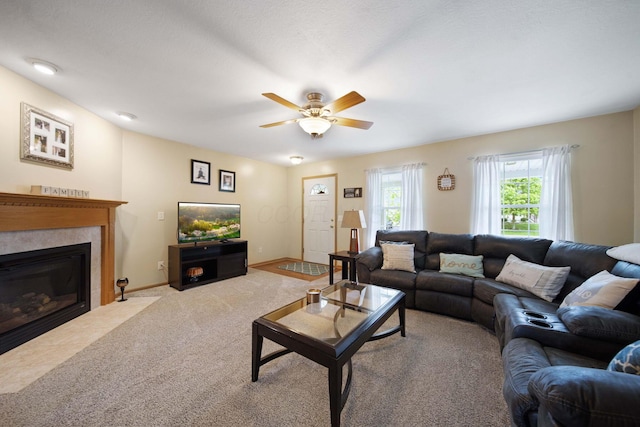 living area with light carpet, ceiling fan, a fireplace with flush hearth, and baseboards