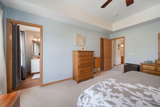 bedroom with light carpet, baseboards, ensuite bath, and a ceiling fan