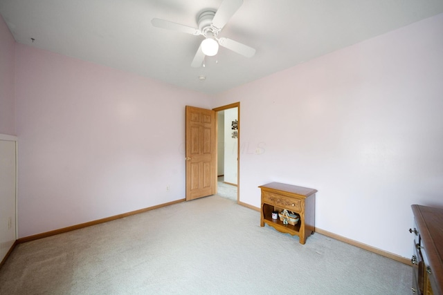 spare room with light colored carpet, ceiling fan, and baseboards