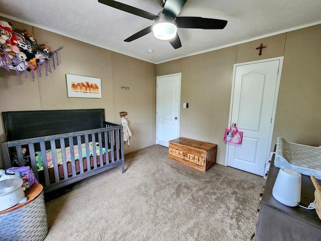 bedroom with carpet flooring, ornamental molding, a crib, and ceiling fan