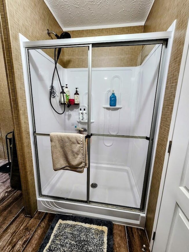 full bath with wood finished floors, a shower stall, and a textured ceiling