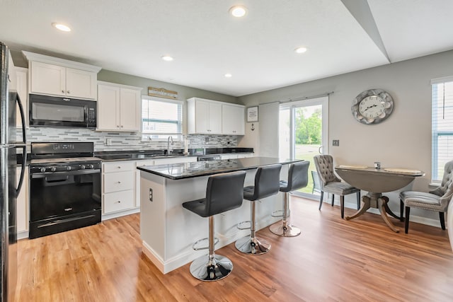 6922 Duke Dr, Canal Winchester, OH 43110 - kitchen featuring black appliances, light wood-style flooring, healthy amount of natural light, a breakfast bar, and recessed lighting