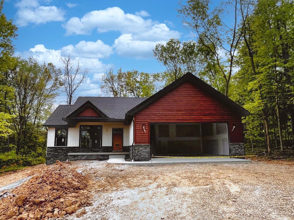 561 Crestmonte Dr, Howard, OH 43028 - view of front of house with stone siding, an attached garage, and dirt driveway