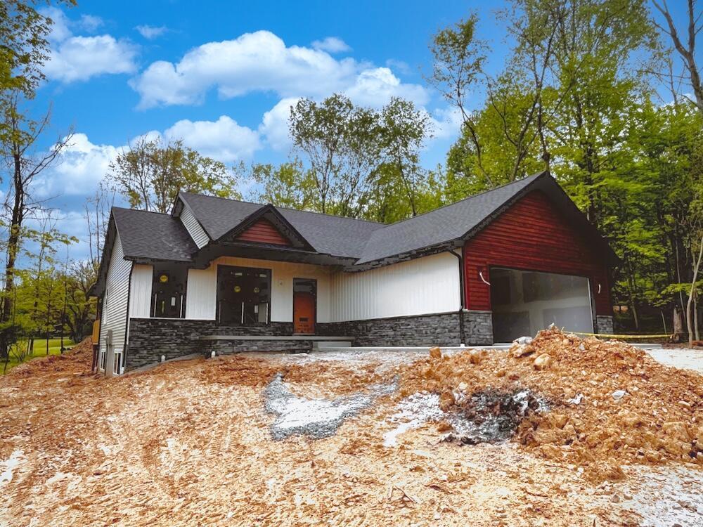 561 Crestmonte Dr, Howard, OH 43028 - view of front of home with stone siding, a garage, and a shingled roof