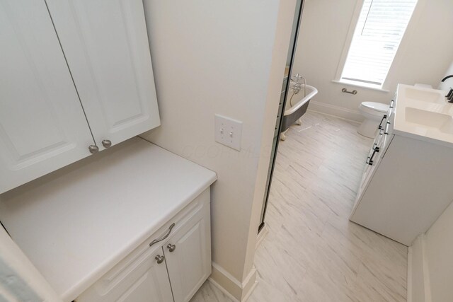 684 Hamlet St, Columbus, OH 43215 - bathroom featuring vanity, a freestanding tub, baseboards, and toilet