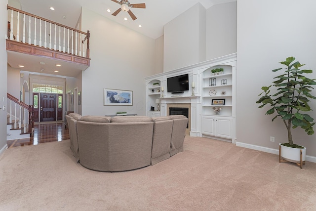1338 Elkhorn Dr, Blacklick, OH 43004 - living area featuring light carpet, a towering ceiling, a glass covered fireplace, a ceiling fan, and stairs