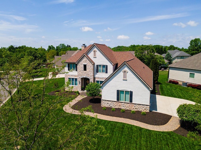 1338 Elkhorn Dr, Blacklick, OH 43004 - view of front of house with stucco siding, stone siding, a chimney, a front yard, and concrete driveway