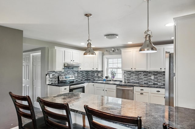 9820 Heimberger Rd NW, Baltimore, OH 43105 - kitchen with stainless steel appliances, a sink, a kitchen bar, white cabinetry, and decorative backsplash