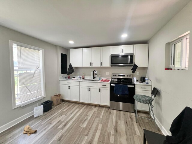 2624 Osceola Ave, Columbus, OH 43211 - kitchen featuring stainless steel appliances, a sink, light wood finished floors, light countertops, and white cabinetry