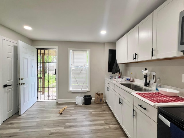 2624 Osceola Ave, Columbus, OH 43211 - kitchen with a sink, light countertops, light wood-style flooring, recessed lighting, and white cabinetry