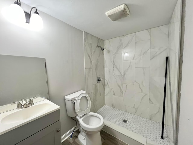 2624 Osceola Ave, Columbus, OH 43211 - bathroom featuring a tile shower, toilet, vanity, and wood finished floors