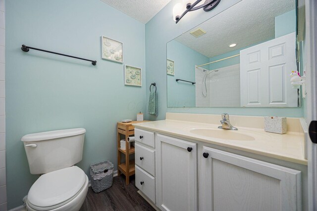 3409 Marl Pl, Columbus, OH 43221 - bathroom with a textured ceiling, wood finished floors, vanity, toilet, and a shower