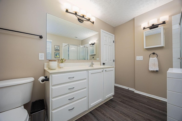3409 Marl Pl, Columbus, OH 43221 - bathroom featuring wood finished floors, vanity, a textured ceiling, toilet, and an enclosed shower