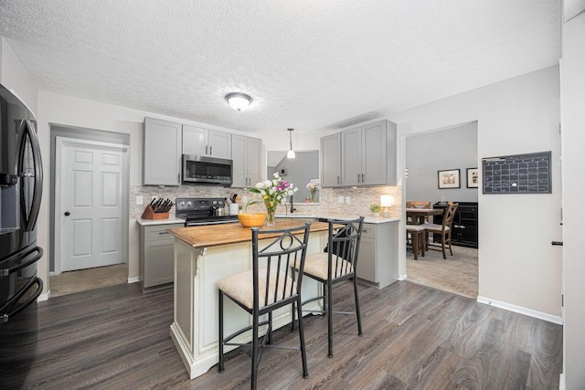 3409 Marl Pl, Columbus, OH 43221 - kitchen featuring black appliances, gray cabinetry, dark wood finished floors, tasteful backsplash, and a textured ceiling